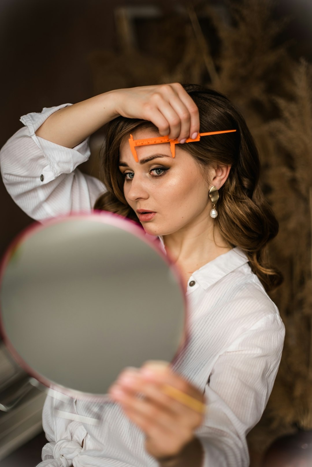 Woman carefully shaping her eyebrow in preparation for beauty or brow treatment
